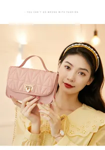 Detailed view of an elegant pink quilted crossbody bag with gold heart-shaped lock held by a model