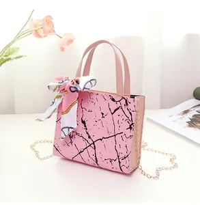 Elegant pink handbag with marble pattern, decorative silk scarf and gold chain strap.