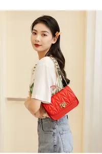 Asian female model wearing a red quilted small square bag with gold chain strap.