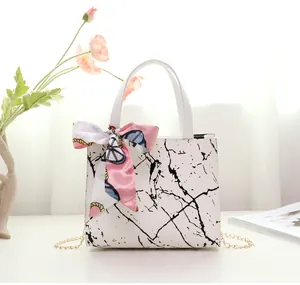 Close-up detail of a white marble pattern handbag with a decorative pink silk scarf bow