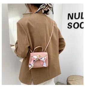 Dettaglio della mini borsa a tracolla rosa con motivo a pietra e foulard di seta decorativo.