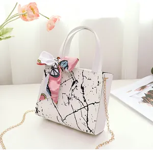 Detail view of a white marble pattern square handbag with a decorative silk scarf
