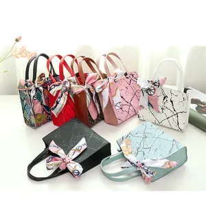 Detail view of trendy small square handbags with silk scarf accents in various patterns.