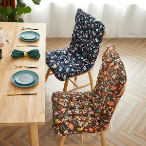 Detailed view of floral and fruit pattern thick integrated chair cushions on wooden chairs