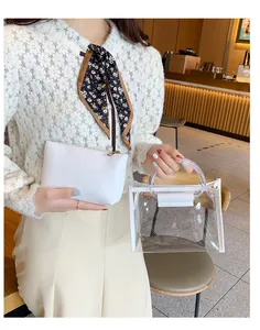 Stylish clear PVC handbag set with white faux leather inner pouch held by model in cafe