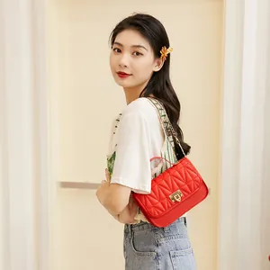 Elegant red quilted crossbody bag with gold chain strap and lock closure on model
