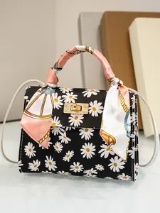 Primo piano di una mini borsa con stampa a margherite e manico avvolto in un foulard
