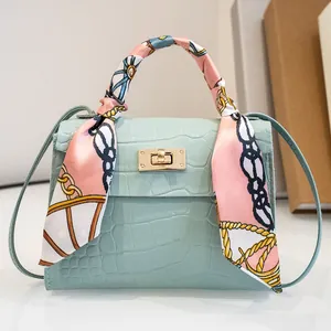 Vista frontale della borsa azzurra motivo pietra con dettaglio foulard rosa