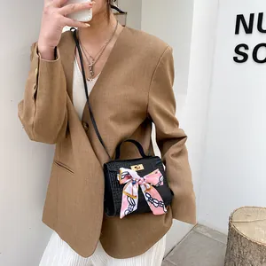 Elegante borsa a tracolla nera con motivo coccodrillo e fiocco in seta rosa su modella