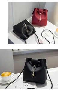 Minimalist black and red bucket bags with a golden deer charm on a cafe table scene