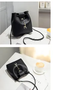 Close-up detail of a black Korean style bucket bag with a gold deer charm pendant.
