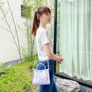 Minimalist purple floral daisy print handbag for women worn by a model in an outdoor setting