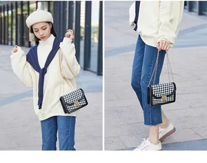 Lifestyle detail of a classic black and white houndstooth crossbody bag with gold chain.