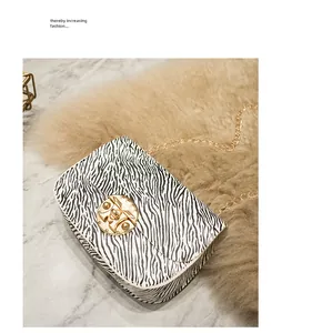 Dettaglio della borsa a tracolla zebrata alla moda con catena d'oro e chiusura tonda.