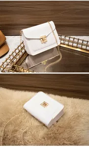 Close-up of white crossbody bag showing gold lock and pebbled texture detail