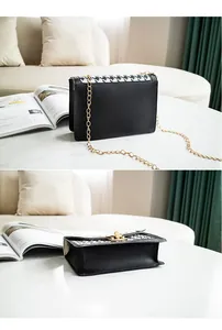 Close-up detail of a black houndstooth pattern crossbody bag with a gold chain strap.