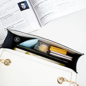 Elegant white flap crossbody bag with gold chain showing organized spacious interior