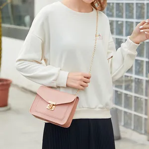 Fashionable pink crossbody square bag with gold chain strap and a secure lock.