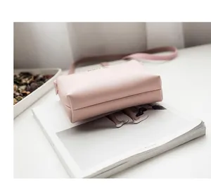 Detail bottom view of a minimalist pink crossbody square bag on a white fashion magazine