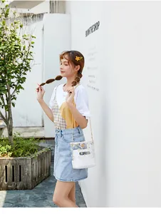 Klarsicht-Umhängetasche mit Gänseblümchen-Print und goldener Kette an einem Modell