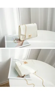 Detail views of a white crocodile embossed small square bag with gold chain strap.