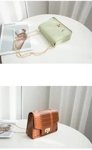 Detail view of crocodile pattern crossbody bags with chain strap and gold lock closure