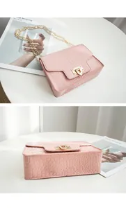 Detailed views of a pink alligator pattern chain crossbody bag on a white table.