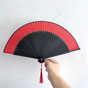 Dettaglio del ventaglio pieghevole cinese rosso e nero con una nappa rossa decorativa