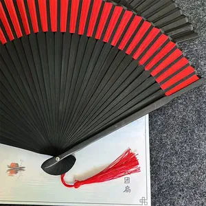 Dettaglio di un ventaglio pieghevole cinese rosso e nero con un accessorio di nappa di seta
