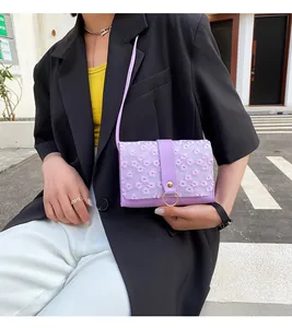 Close-up of a purple small square bag with elegant floral embroidery and gold ring closure.