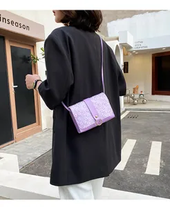 Detailed view of a small purple flower lace crossbody bag styled with a black blazer