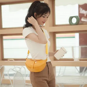 Stylish yellow crocodile pattern saddle bag worn by a model in a cafe setting