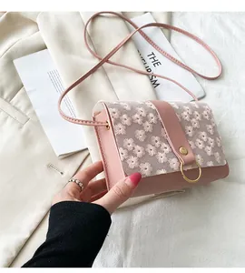 Detailed close-up of pink crossbody bag with exquisite embroidered daisy flower pattern