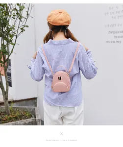 Back view of a model wearing a stylish pink mini leather backpack with cute bunny ears