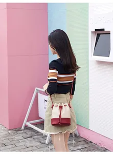 Back view of model wearing a stylish two-tone quilted drawstring bucket bag outdoors