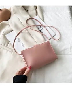 Close-up of a pink minimalist crossbody bag with floral detail on the flap
