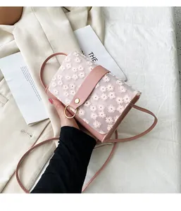 Detailed view of pink crossbody bag with delicate white daisy embroidery