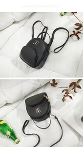 Close-up of minimalist black leather mini backpack on white bedding background.