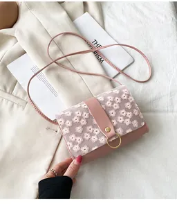 Close-up of pink small square bag featuring delicate floral embroidery and gold ring.
