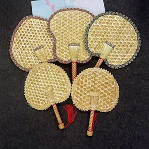 Traditional handmade woven straw fans with colorful fabric borders and red tassels