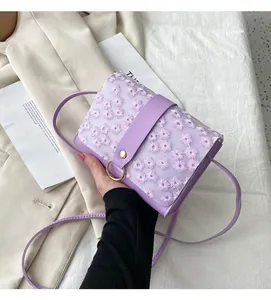 Detail view of a purple crossbody bag featuring delicate floral embroidery and gold ring hardware