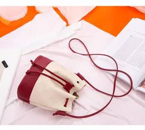 Top view detail of cream and burgundy quilted drawstring bucket bag with gold eyelets