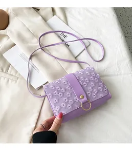 Detail shot of a purple crossbody bag with delicate floral embroidery and gold ring clasp.