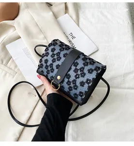 Detailed macro view of a small floral crossbody phone bag featuring a gold ring buckle.
