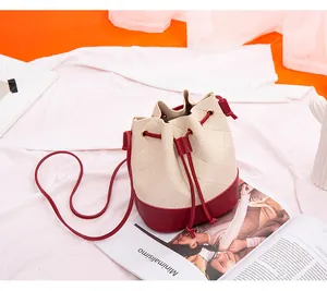 Detail of a cream and red color-blocked drawstring bucket bag with quilted texture.