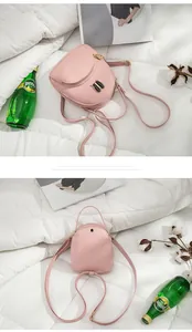 Close-up of pink mini backpack with cute hardware detail on white textured background