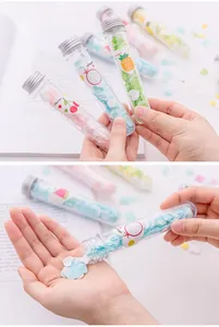 Hand showing colorful heart-shaped paper soap flakes being poured from a clear test tube.