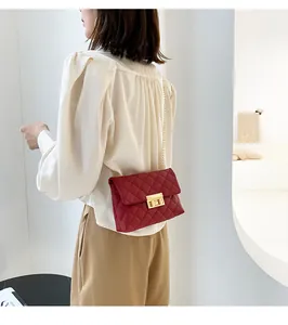 Red quilted chain crossbody bag with gold lock detail on woman's shoulder