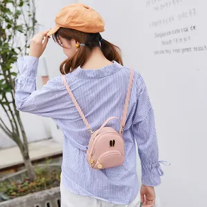 Cute pink mini backpack with metallic rabbit ears worn by a female model outdoors