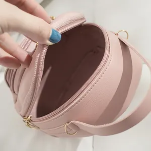 Pink circular mini crossbody bag showing internal zipper compartment detail